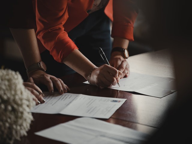 dos personas firmando documentos